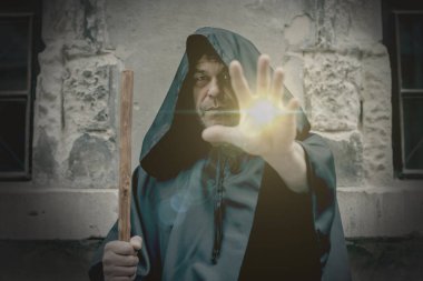 Işık ve güç siyah cüppeli yaşlı bir keşişin elinden gelir. Kavram: Şifa ve büyü, lanetler ve kutsama. .