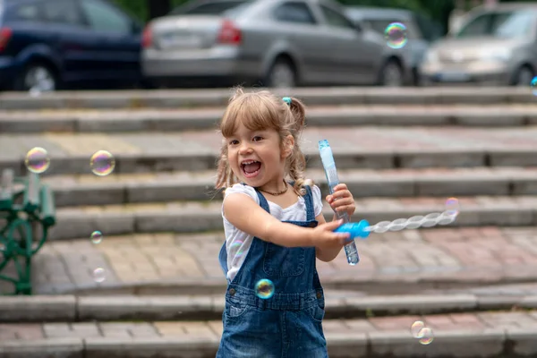 ブロンドの髪を持つ3 4歳の少女は 路上で石鹸泡を吹く 夏と休日の子供向けエンターテイメント — ストック写真