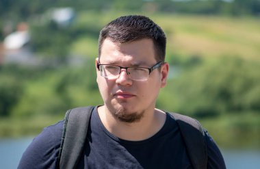 25-30 yaşlarında ciddi bir gencin sokak portresi. Sırt çantasıyla doğanın arka planına bakıyor. Belki de bir turist ya da gezgindir. Tatil yapan bir bilişim uzmanı..