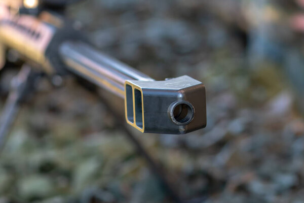 Бочка снайперской винтовки лежит крупным планом на камуфляжном покрытии.