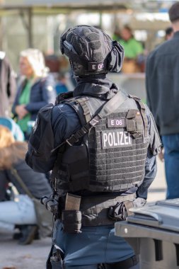 Kurşun geçirmez yelek giyen bir polis komandosu şehir ortamındaki durumu izliyor. Avusturya, Viyana, 26 Ekim 2025.