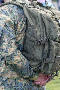 Kamuflaj üniformalı bir askerin sırtında büyük bir ordu çantası var.