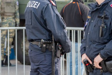 Üniformalı adamlar şehrin caddesinde, kalabalığın ve metal bir çitin yanında. Avusturya, Viyana, 26 Ekim 2025