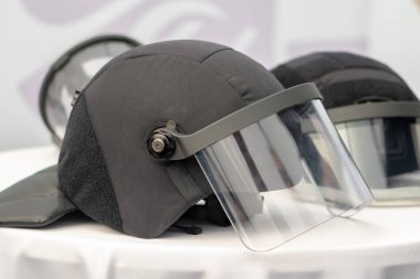 Masada başka bir koruyucu kaskın yanında şeffaf büyük vizörlü bir polis kaskı var.