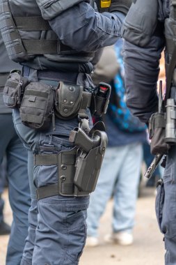 Taktiksel ekipmanlar polisin kemerine yerleştirilir, bir tabanca kılıfı ve keseler de dahil.