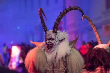 Krampus 'un heybetli boynuzları seyirciler arasında kalın dekoratif bir sis içinde caddede yürüyordu.