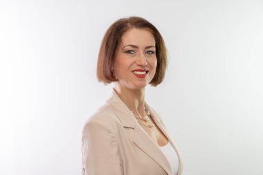 Orta yaşlı bir kadın beyaz bir arkaplan önünde kendinden emin, dostane bir gülümseme sergiliyor.