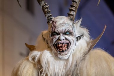 Krampus 'un boynuzları ve parlak gözleri tören sırasında seyirciye bakıyor.
