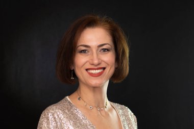 Stüdyo portresi. Orta yaşlı bir kadın. Zarif, parlak bir elbise giymiş.