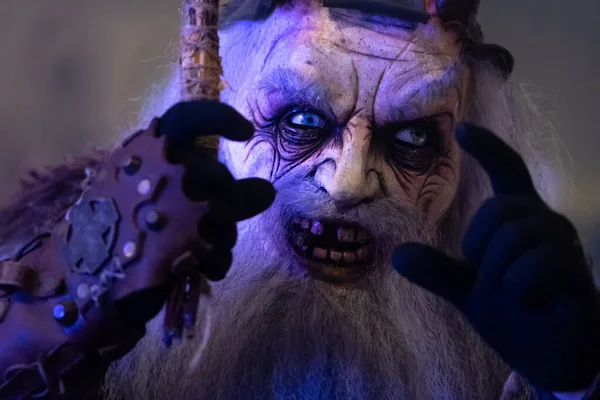 Krampus 'un kaldırılmış elleri ve gergin yüz ifadesi soğuk ışık altında yakından görülüyor