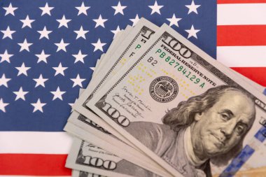 Amerikan bayrağının arka planında 100 dolarlık banknotlar.