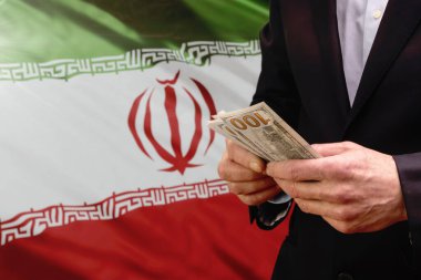 İran bayrağının önünde Amerikan doları tutan adam..