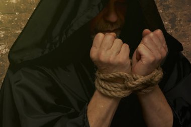 Keşiş elleri koyu arkaplanda tespih tutuyor..