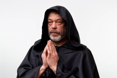 Yaşlı erkek keşiş beyaz stüdyo arka planında tek başına namaz kılıyor.