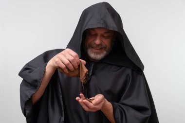 Yaşlı keşiş gülümserken beyaz arka planda bir bağış kesesi tutuyor.