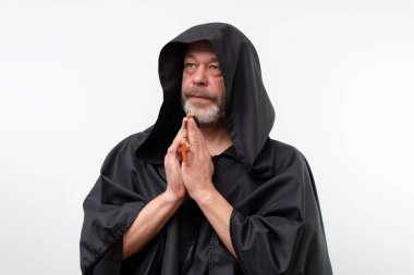 Siyah cüppeli yaşlı keşiş elleri bağlı tespihi tutuyor.