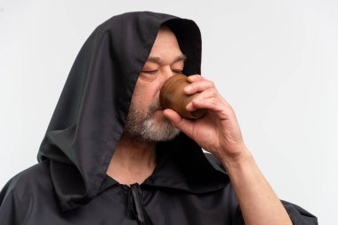 Kapüşonlu sakallı keşiş beyaz arka planda içki içiyor..