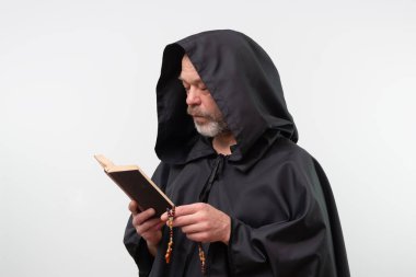 Kapüşonlu sakallı keşiş beyaz arka plan üzerine dini kitaplar okuyor.