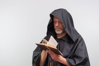 Erkek keşiş kitap okuyor, siyah cübbe giyiyor, izole edilmiş.