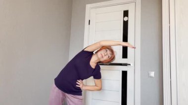 Son sınıf öğrencisi, altmış yaşında. Vücudunu esnetiyor. Kolunu başının üstüne kaldırıyor.