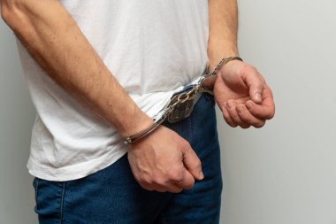 Elleri kelepçeli bir adam kameraya yan dönmüş.