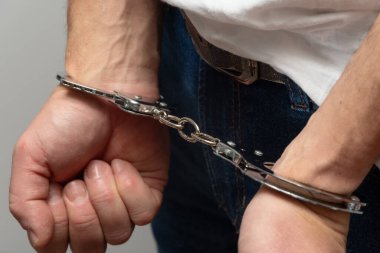 Kelepçe takarken yumruk sallayan bir adam.