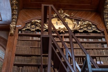 Avusturya, Viyana, 6 Ağustos 2025: Kitap raflarının önündeki metal kütüphane merdiveni ve Avusturya Ulusal Kütüphanesi 'nin Barok iç mekanındaki yaldızlı dekoratif panel