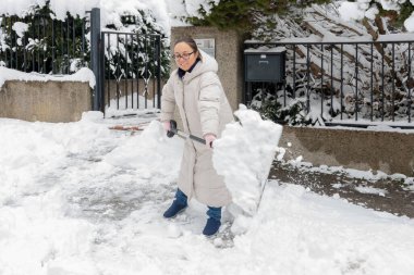 Ev sahibi soğuk havada kardan mülke girişi temizliyor.