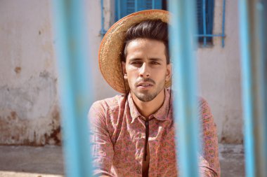 parmaklıklar arkasında şapkalı yakışıklı adam