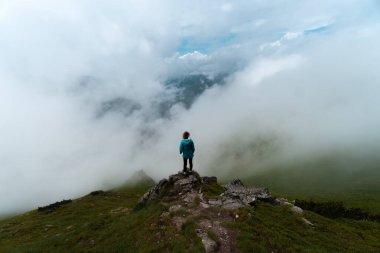 Tatra Dağları 'nda, Polonya ile Slovakya arasındaki sınırda sisli ve bulutlu bir günde bir dağ geçidinde yürüyüş yapan bir kız. Mavi ceket..