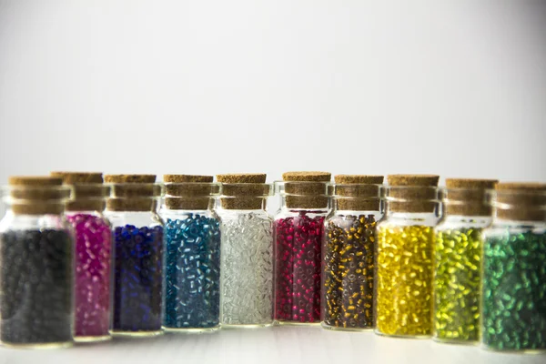 Крошечные стеклянные бутылки, наполненные бусами разных цветов — стоковое фото