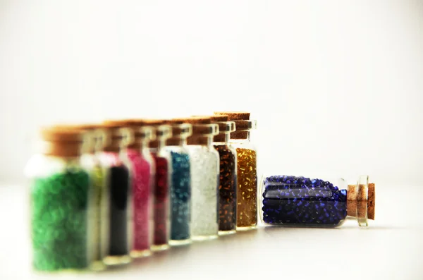 Malé skleněné láhve naplněné korálky různých barev — Stock fotografie