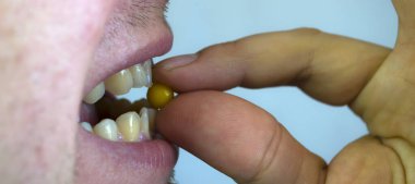 Bir erkek ağzına vitamin alır, hastalıklardan korur..