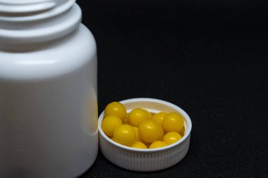 Vitaminler ve arka planda beyaz bir kavanoz..