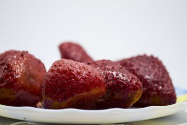 Donmuş çilekler, beyaz bir arka planda, bir fincan tabağında yatıyor..