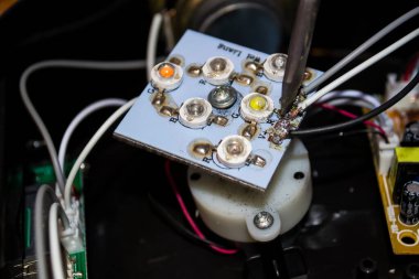 Tahtadaki kabloları lehim demiriyle sabitle. Makineler tamir ediliyor.