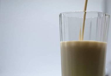 Bardakta ev yapımı mayalanmış içecek kefir, süzme peynir, beyaz arka planda. Ekşi süt içeceği, maya mayası mayası, bağırsak sağlığı konsepti. Modaya uygun yiyecek ve içecekler.