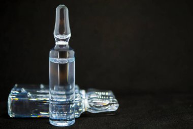 İğne için cam ampul şişesi. İlaç sıvı sodyum klorürdür. Ampullada su çözeltisi bulunur. Kapatın. Arka plan rengi ve su üzerindeki şişeler çok renkli. İnsan plazması.