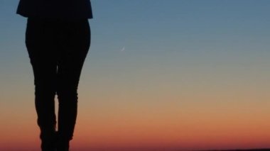 Gün batımında kız kıyıda duruyor ve uzaklara bakıyor, bir mucize bekliyor..