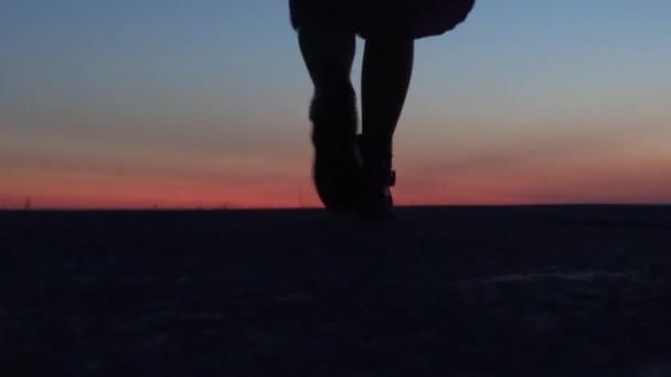 Το κορίτσι στο ηλιοβασίλεμα στέκεται στην ακτή και κοιτάζει μέσα στην απόσταση, περιμένοντας ένα θαύμα.. — Αρχείο Βίντεο