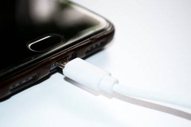 Beyaz arkaplanda şarj aleti olan akıllı telefon, USB kablosu