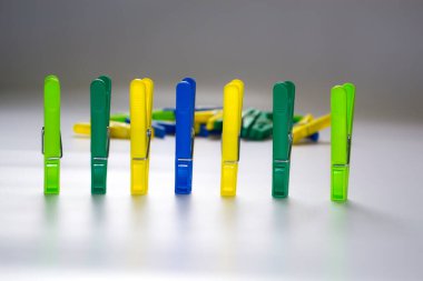 Hafif arka planda renkli plastik mandallar. Yazıtın için yer aç. Minimalizm, orijinal ve yaratıcı fotoğrafçılık. Farklı ol. Bireysellik kavramı. Bir için dikey duvar kağıdı