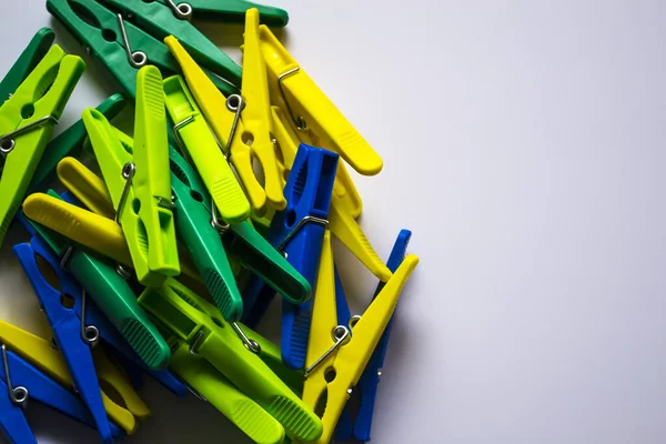 Hafif arka planda renkli plastik mandallar. Yazıtın için yer aç. Minimalizm, orijinal ve yaratıcı fotoğrafçılık. Farklı ol. Bireysellik kavramı. Bir için dikey duvar kağıdı