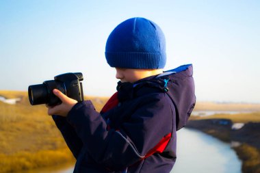 Bir çocuk elinde bir kamera tutuyor, bahar akşamının doğasını filme çekiyor..