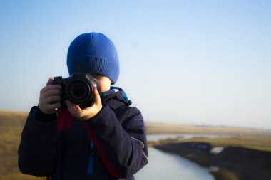 Bir çocuk elinde bir kamera tutuyor, bahar akşamının doğasını filme çekiyor..