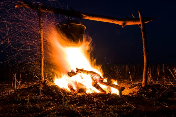 Cozinhar na fogueira para acampar. Pote sobre um fogo ao ar livre. O romance do turismo selvagem e comida no acampamento. Mochila na natureza ao pôr do sol. — Fotografia de Stock