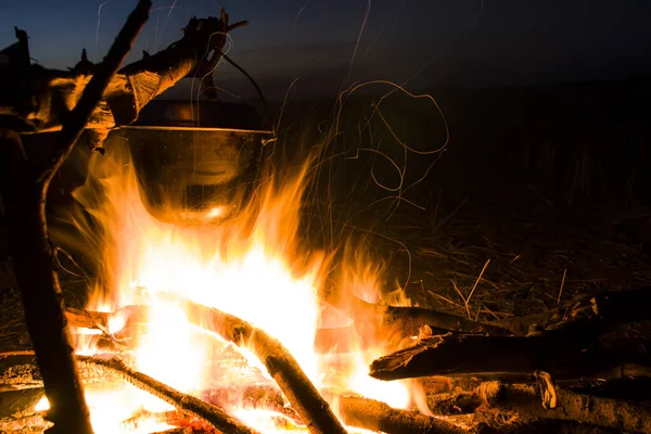 Cooking on the fire for a camping trip. Pot over a fire outdoors. The romance of the wild tourism and food in camp. Backpacking on the nature at sunset. — Stock Photo, Image