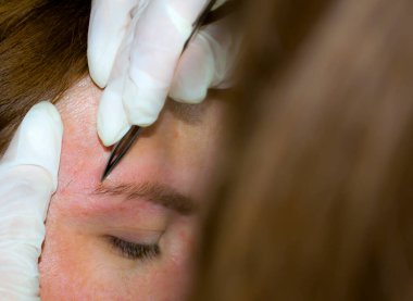 Bir kız pandemik iletişim evinde kaş düzeltmesinden geçiyor. Ev işleri.