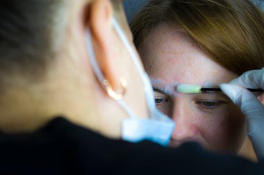 Bir kız pandemik iletişim evinde kaş düzeltmesinden geçiyor. Ev işleri.