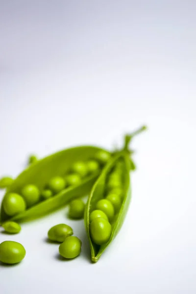 Grüne Erbsen in Hülsen auf weißem Hintergrund, gesunde vegetarische Kost. — Stockfoto